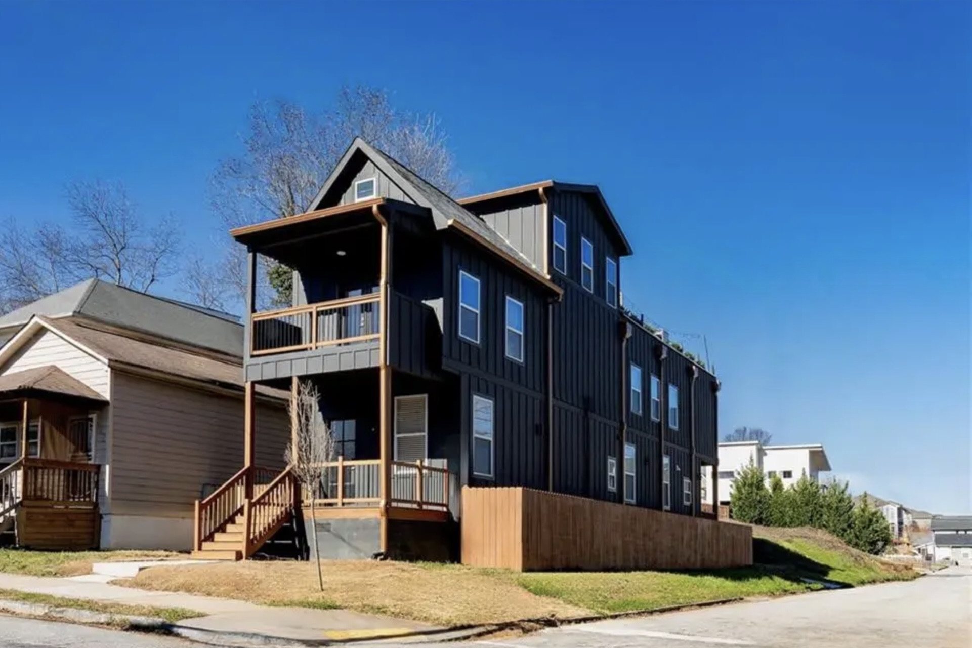 Finished three-story black board-and-batten home with stacked porches and copper trim