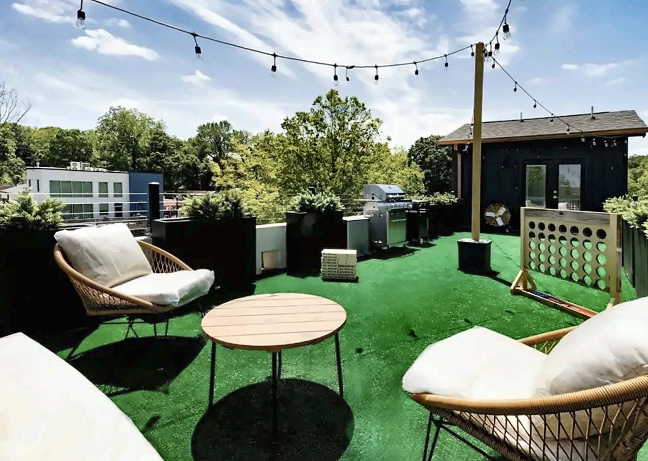 Rooftop deck with turf, lounge chairs, string lights and the rooftop room