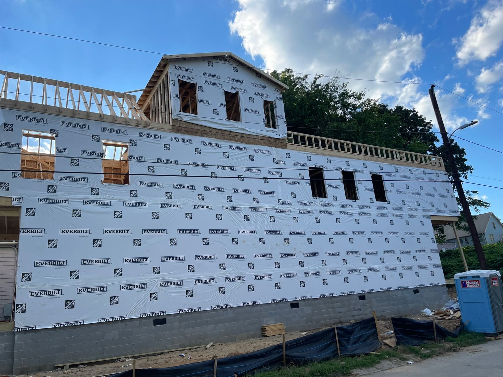 House fully wrapped in weather barrier with rooftop room framed