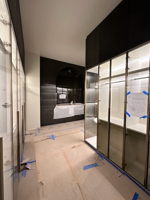 Walk-in closet with glass-front wardrobes and an arched vanity